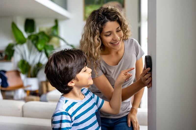 woman teaching her son how to use the thermostat